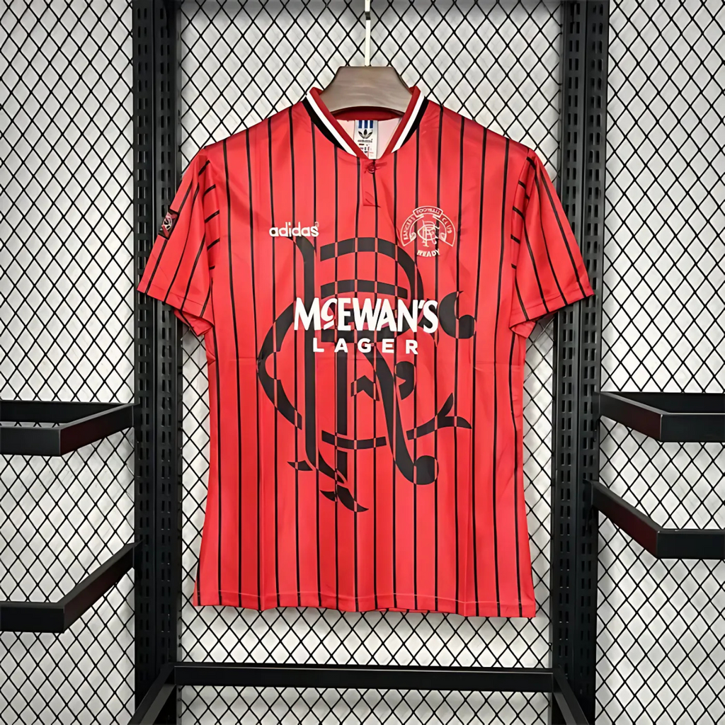 Red Rangers FC football away jersey from 1994/95 with black stripes, made by Adidas and sponsored by McEwan's lager on a hanger against a grid background
