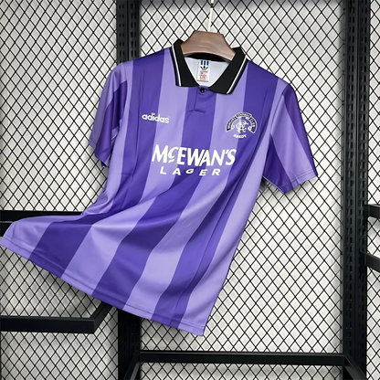 Striped Purple Rangers FC away sports jersey from 1994/95 with Adidas logo and McEwan's Lager text on a hanger against a grid background.