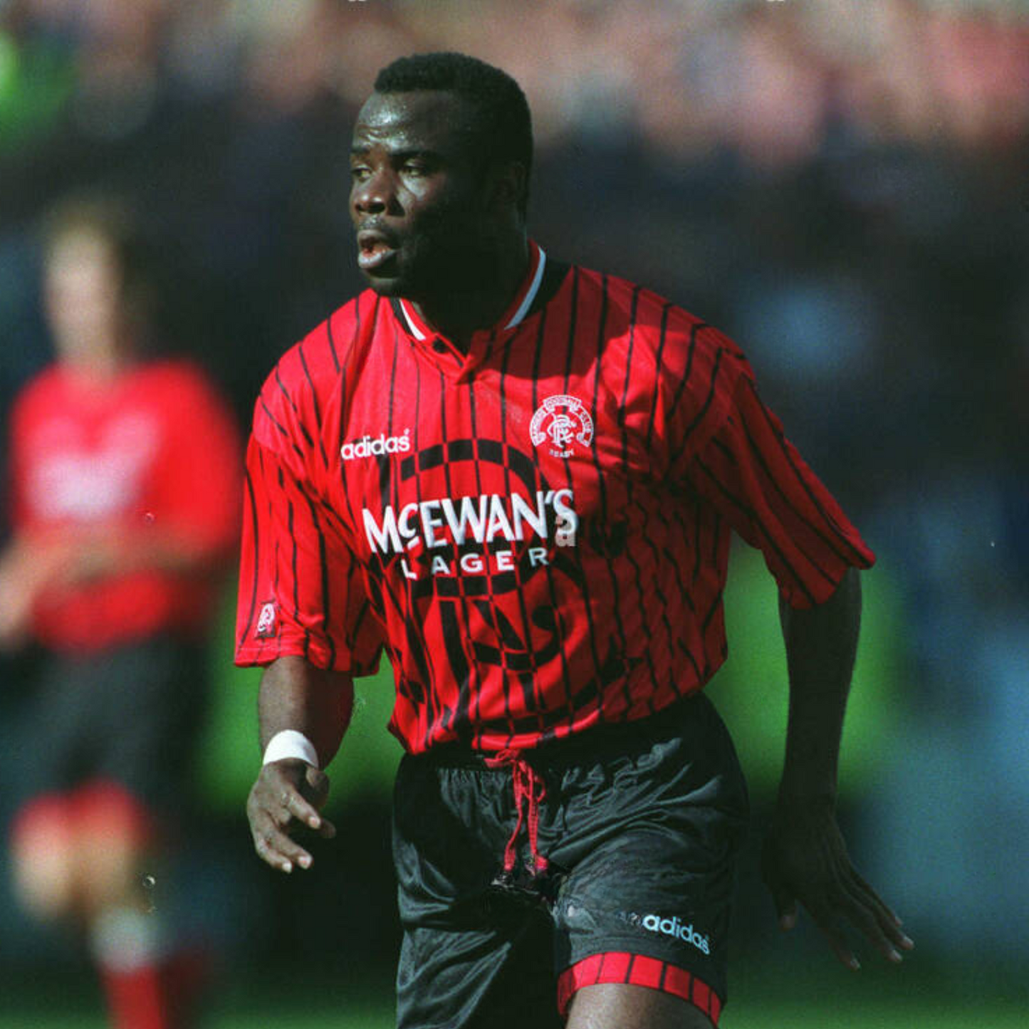 Red Rangers FC football away jersey from 1994/95 with black stripes, made by Adidas and sponsored by McEwan's lager being worn by a rangers player during a football match