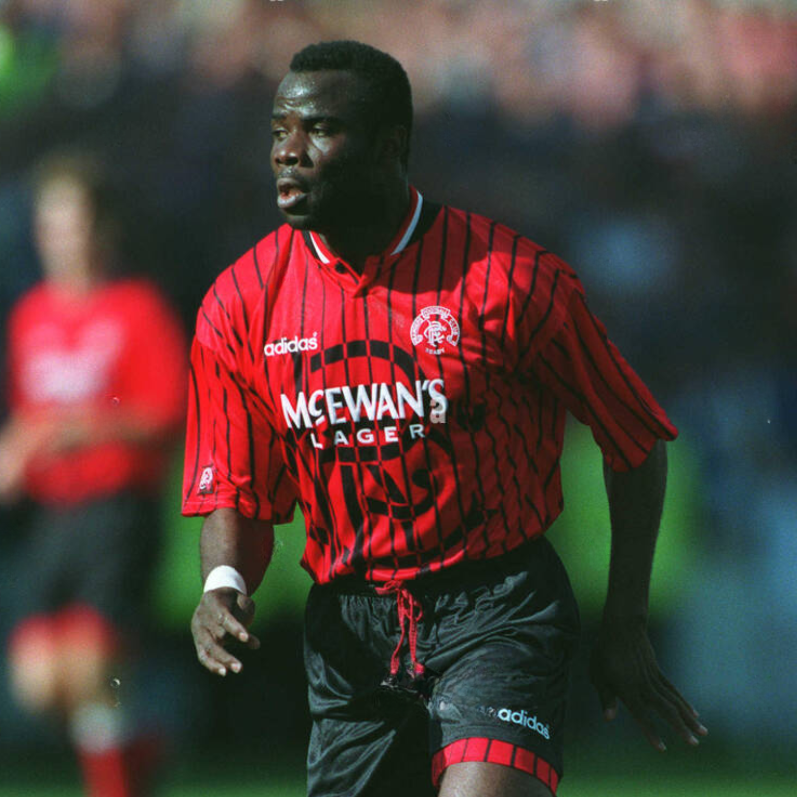 Red Rangers FC football away jersey from 1994/95 with black stripes, made by Adidas and sponsored by McEwan's lager being worn by a rangers player during a football match