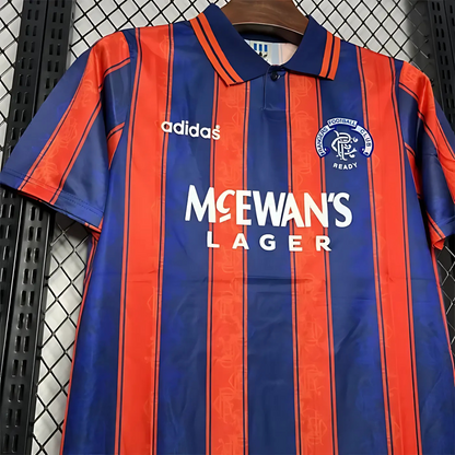 Blue and orange striped Rangers retro vintage sports jersey from 1994/95with Adidas and McEwan's Lager branding on a black metal surface.